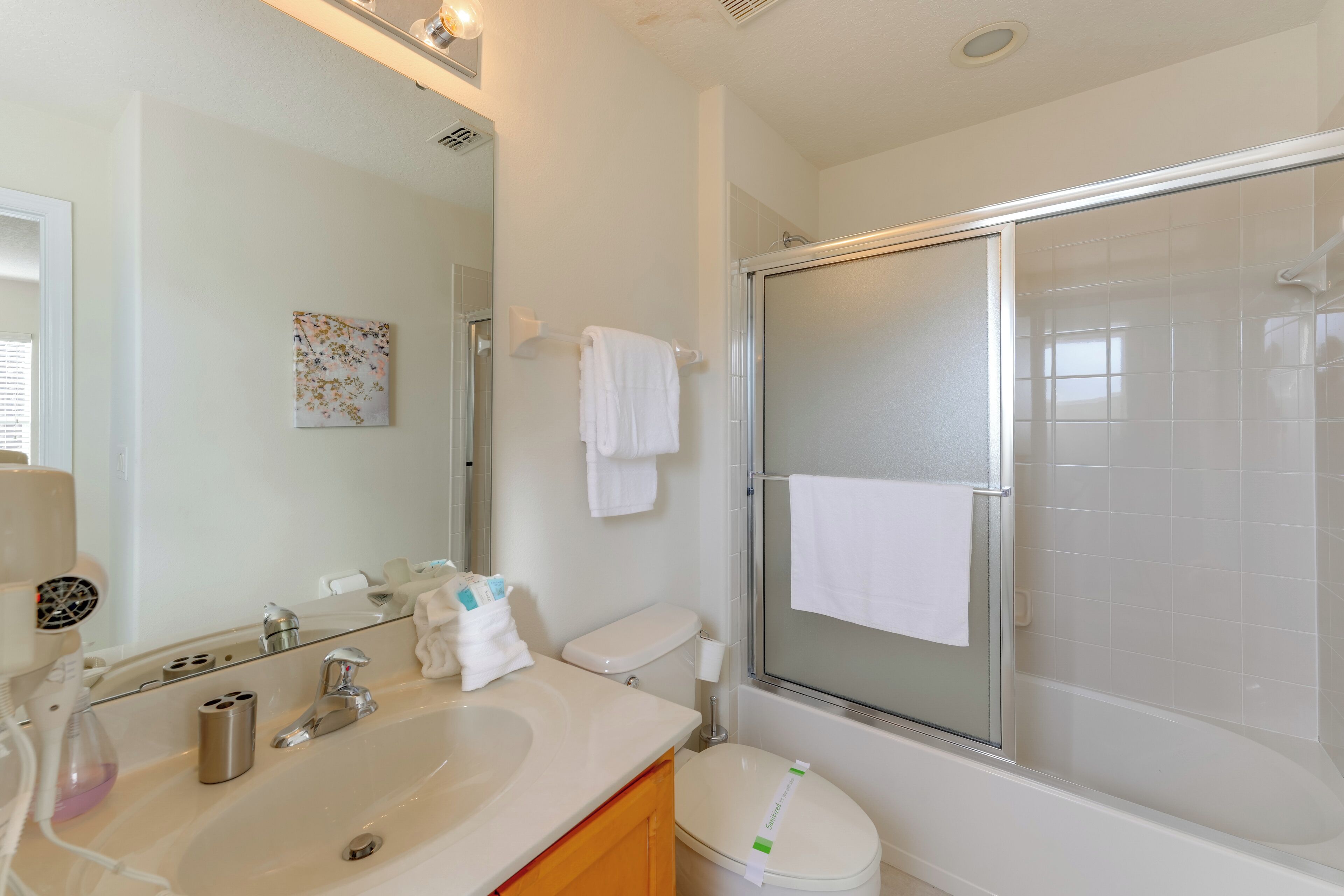 Un baño con lavamanos, espejo, inodoro y cabina de ducha de vidrio.