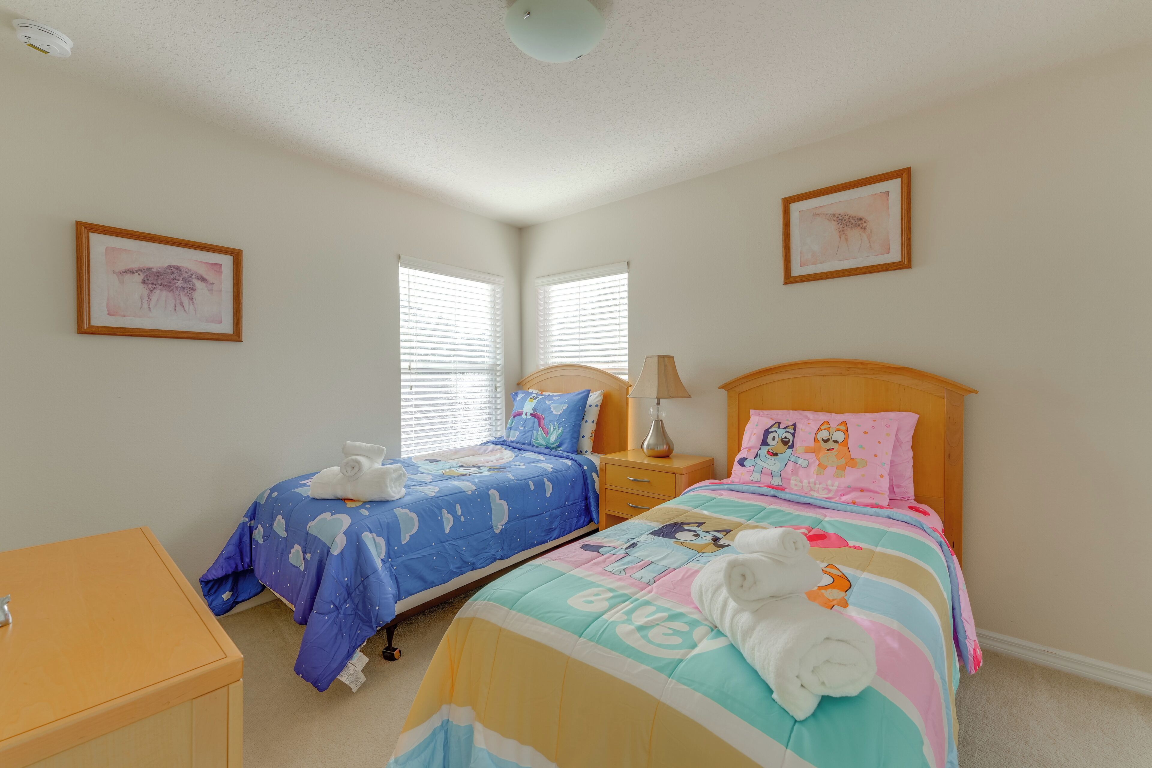Une chambre avec deux lits, une table de chevet en bois, une commode et une petite commode à tiroirs.