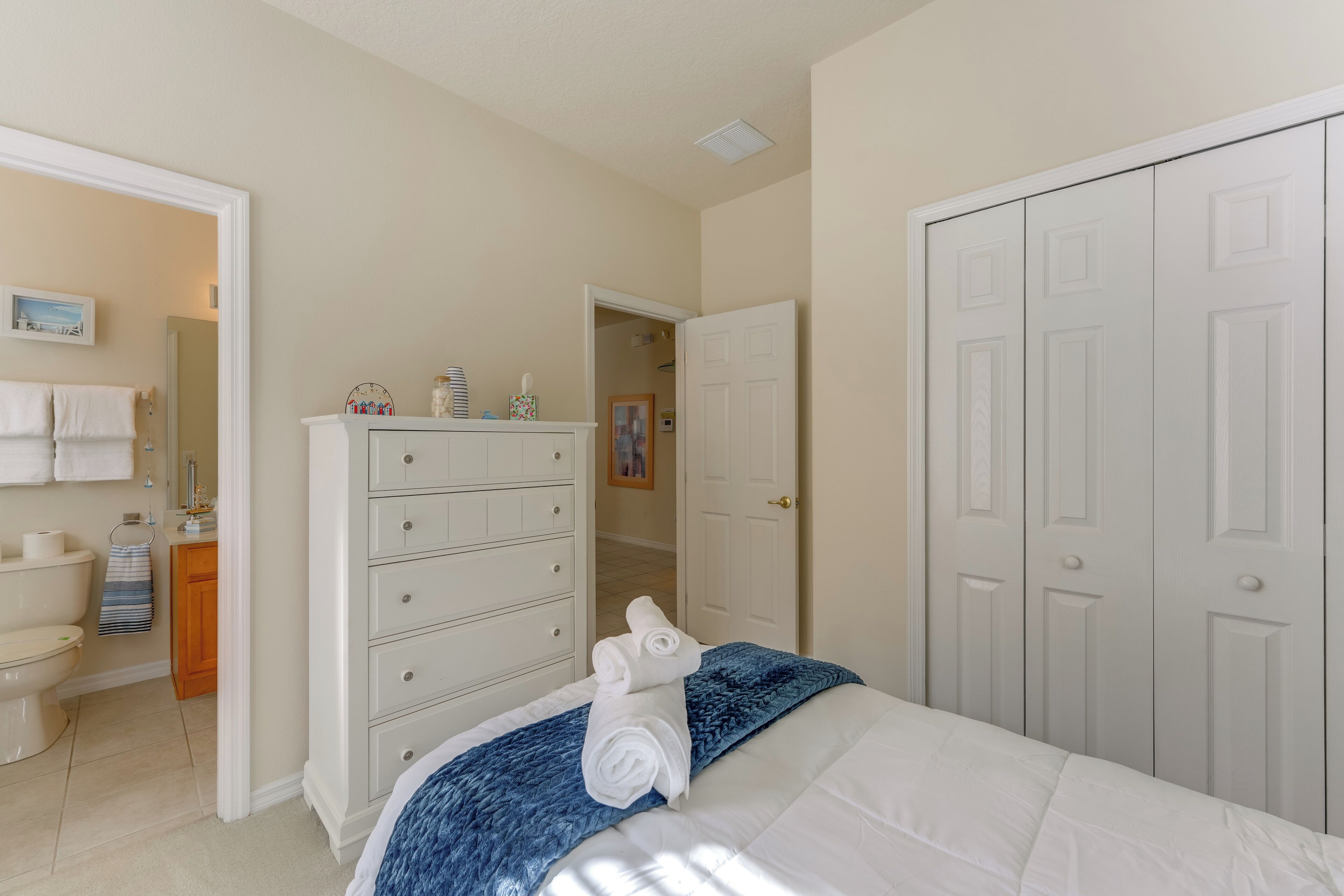 Un dormitorio con cama, cómoda, armario y baño.
