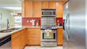 A kitchen with wooden cabinets, stainless steel appliances, granite countertops, and a dishwasher. - Walk to Beach! Treasure Island Gem w/ Water Views (Treasure Island)