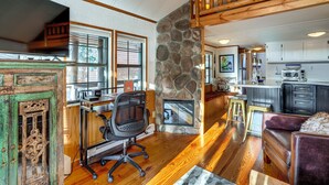A spacious living area with a stone fireplace, wooden flooring, and a kitchen in the background. - 4 Mi to Slopes! Breck Mtn Base w/ Hot Tub Access (Breckenridge)