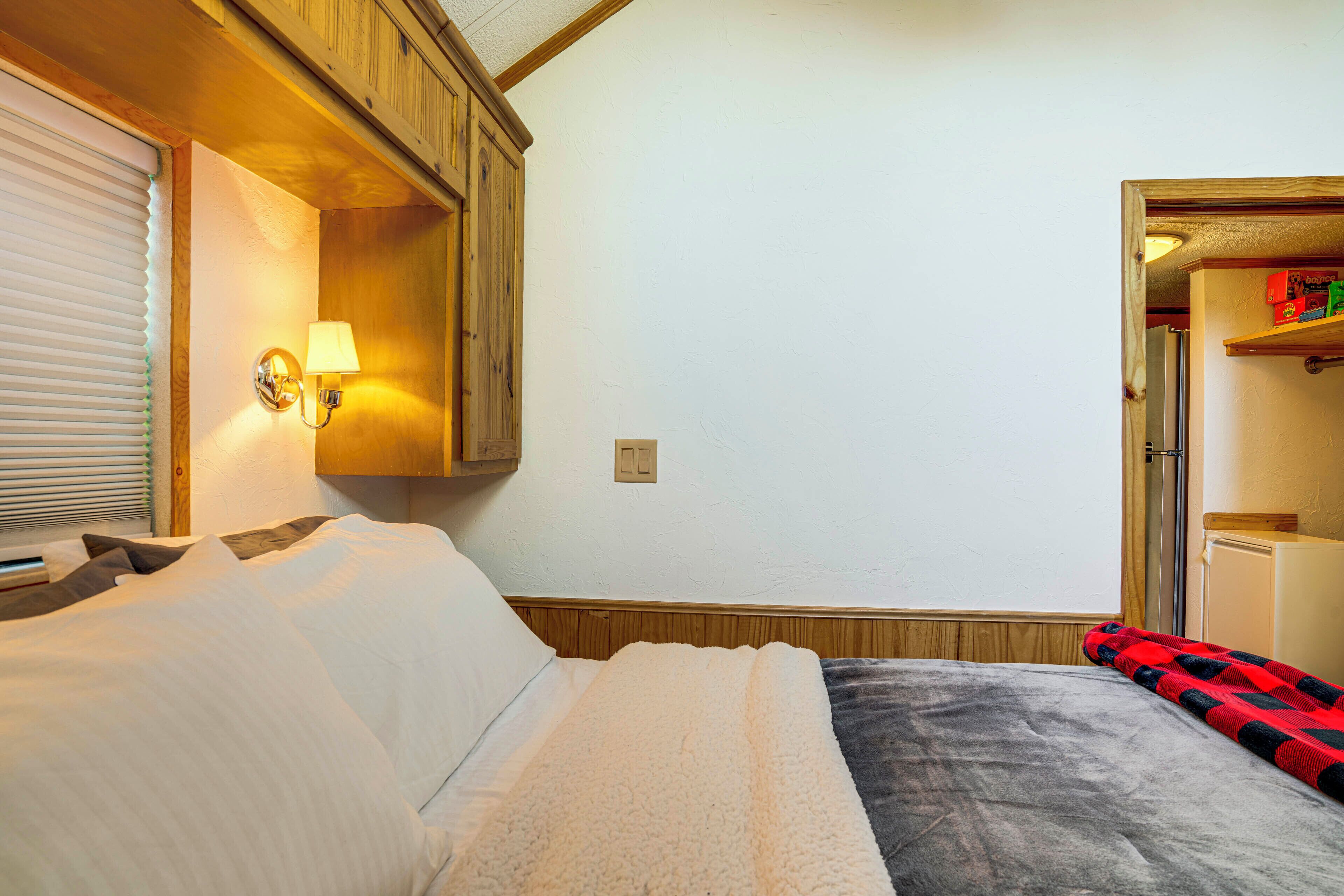 A bedroom with a bed, a nightstand, a lamp, and a wooden ceiling.