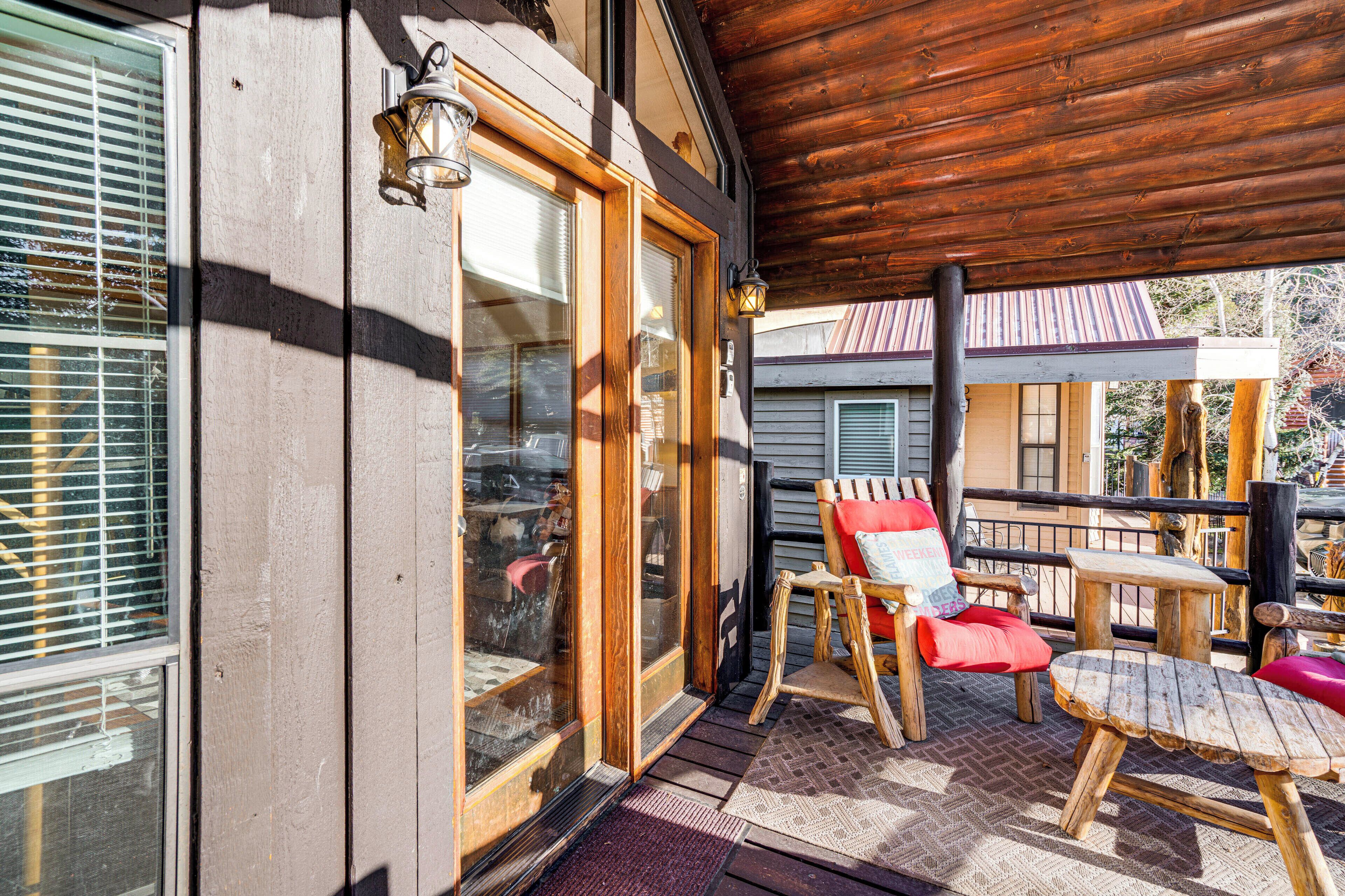 Une terrasse en bois dotée d’un espace salon couvert, d’une entrée avec porte vitrée et offrant une vue sur un immeuble voisin.