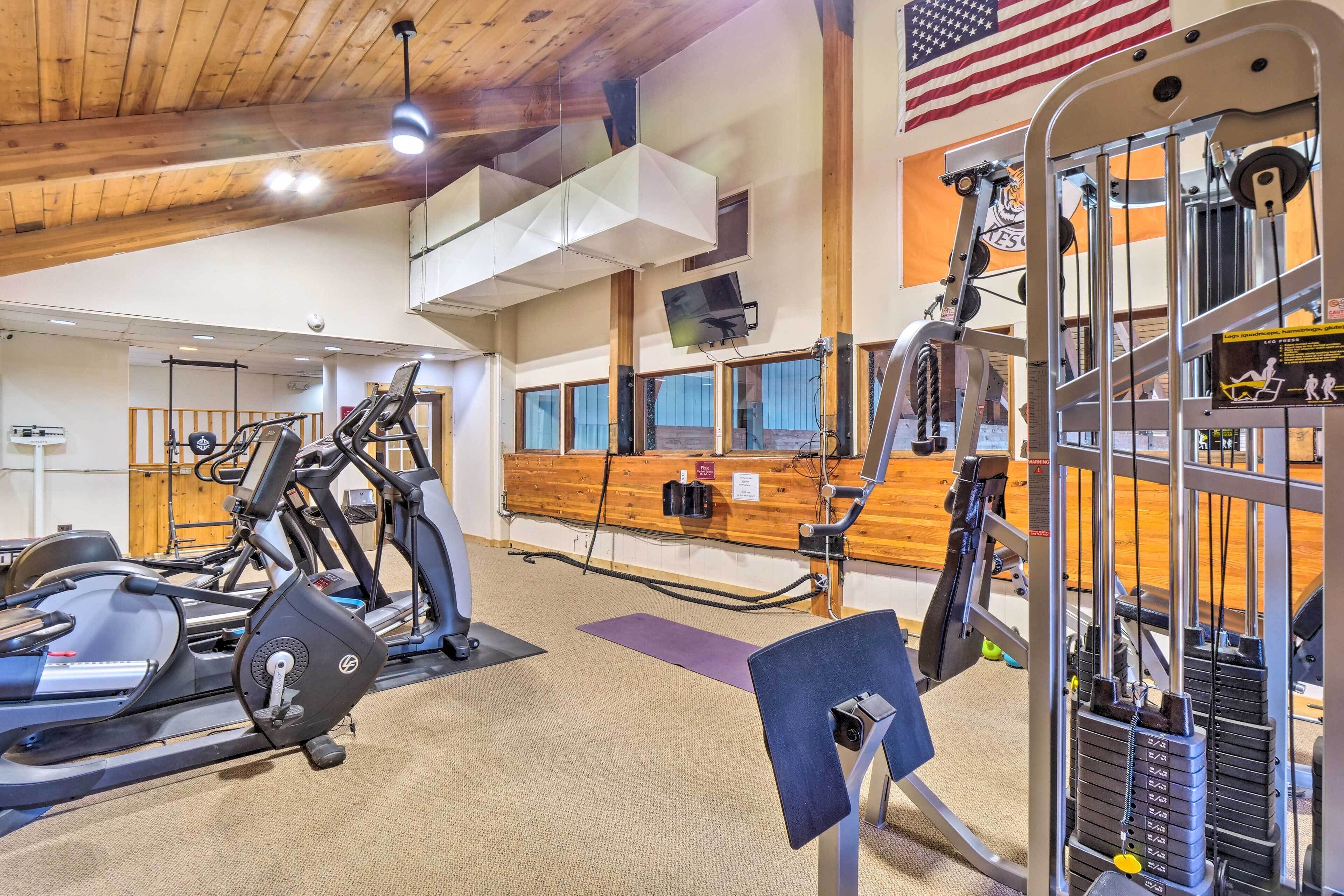 Une salle de sport équipée de divers appareils d’exercice, notamment des tapis de course et des appareils de musculation, et dotée d’un comptoir d’accueil en bois.