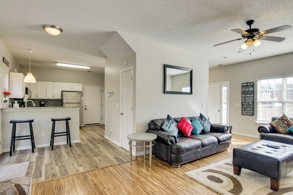 A modern living room with a leather sofa, a round coffee table, and a ceiling fan. - Quiet Oasis in Charlotte! Home Near Uncc Campus (Charlotte)