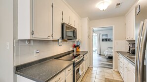 Une cuisine moderne avec des meubles blancs, un four à micro-ondes, une cuisinière et un réfrigérateur.