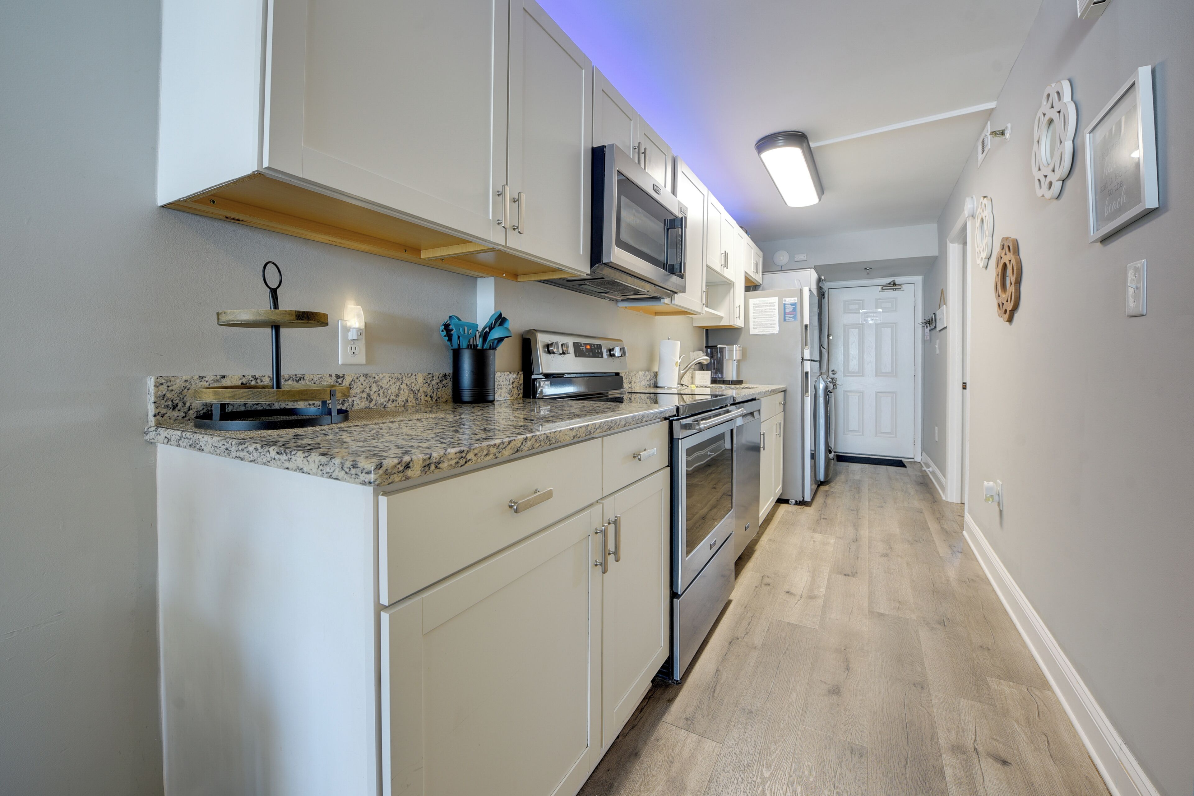 A modern kitchen with white cabinets, stainless steel appliances, and a granite countertop.