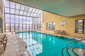 Une piscine intérieure avec des parois en verre transparent, un panneau indiquant l’absence de maître-nageur et un indicateur de profondeur indiquant 3 pieds.
