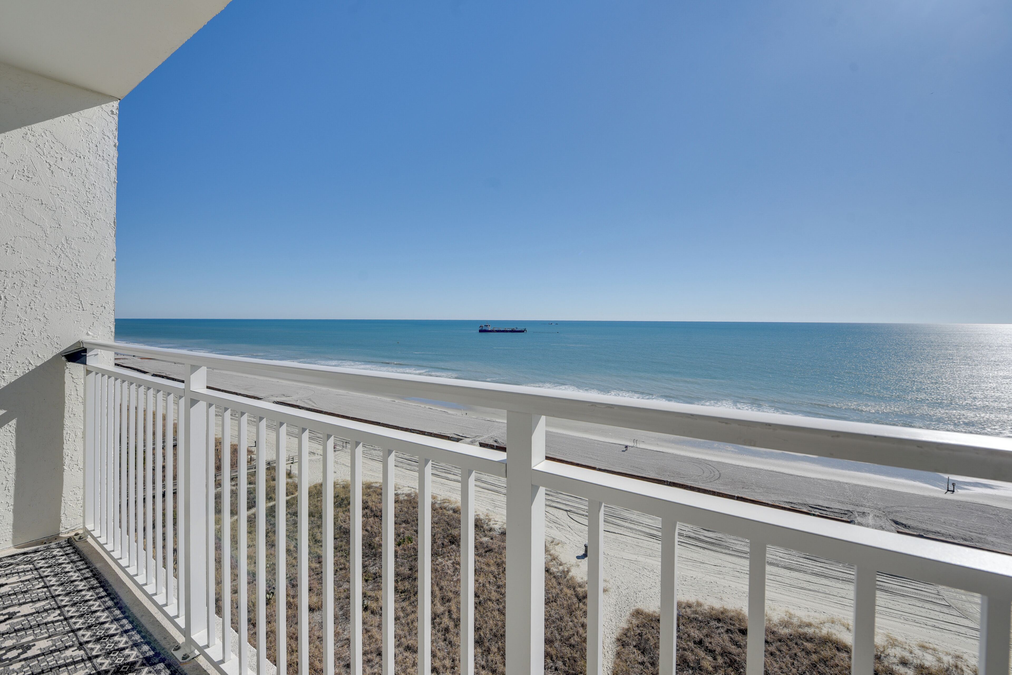 A balcony with a view of the beach and ocean.