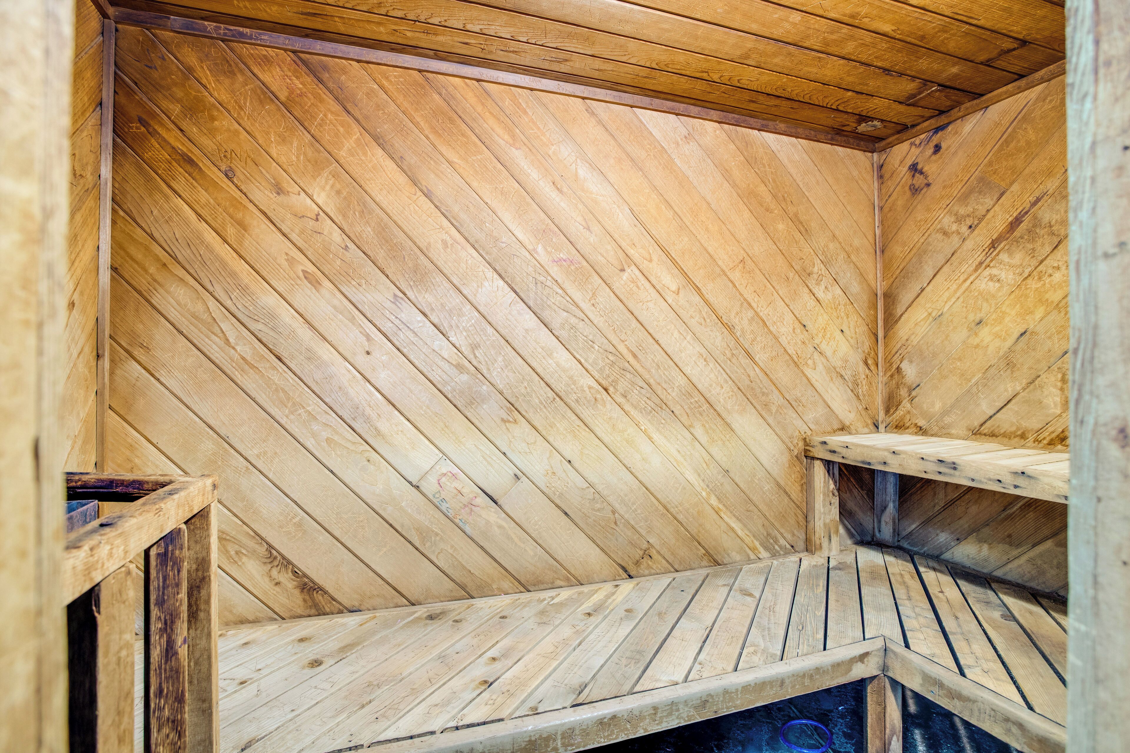 A wooden sauna with slatted benches and a visible heating element.