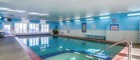 An indoor swimming pool with clear blue walls, a tiled floor, and a lifeguard station.