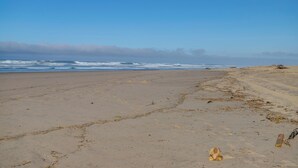 Een strand met zand, golven en een heldere lucht.