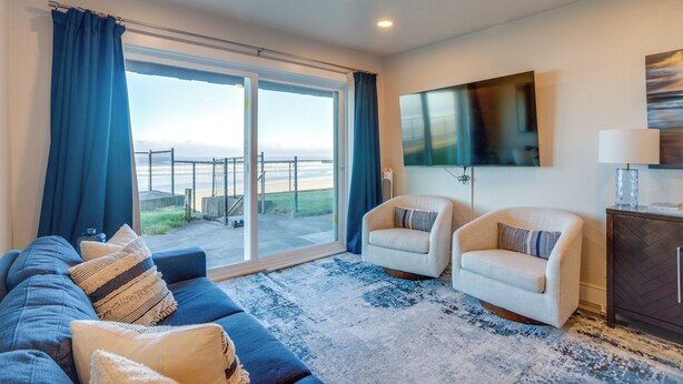Een woonkamer met een bank, twee fauteuils, een televisie en uitzicht door een schuifpui.