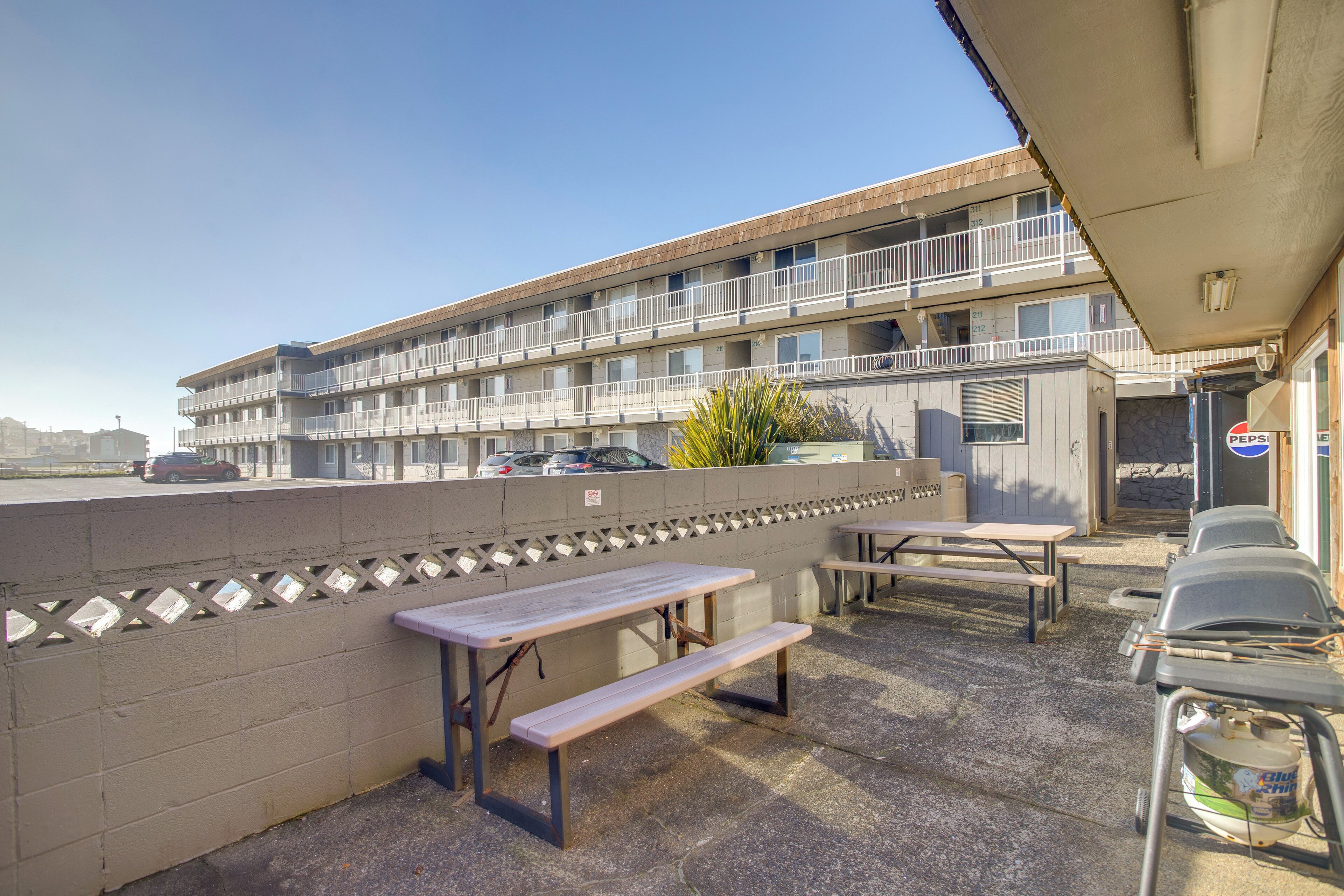 A motel with outdoor picnic tables and a parking lot.