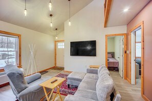 Ein modernes Wohnzimmer mit einem grauen Sofa, einem Holztisch und einem flachbildfernseher an der Wand.