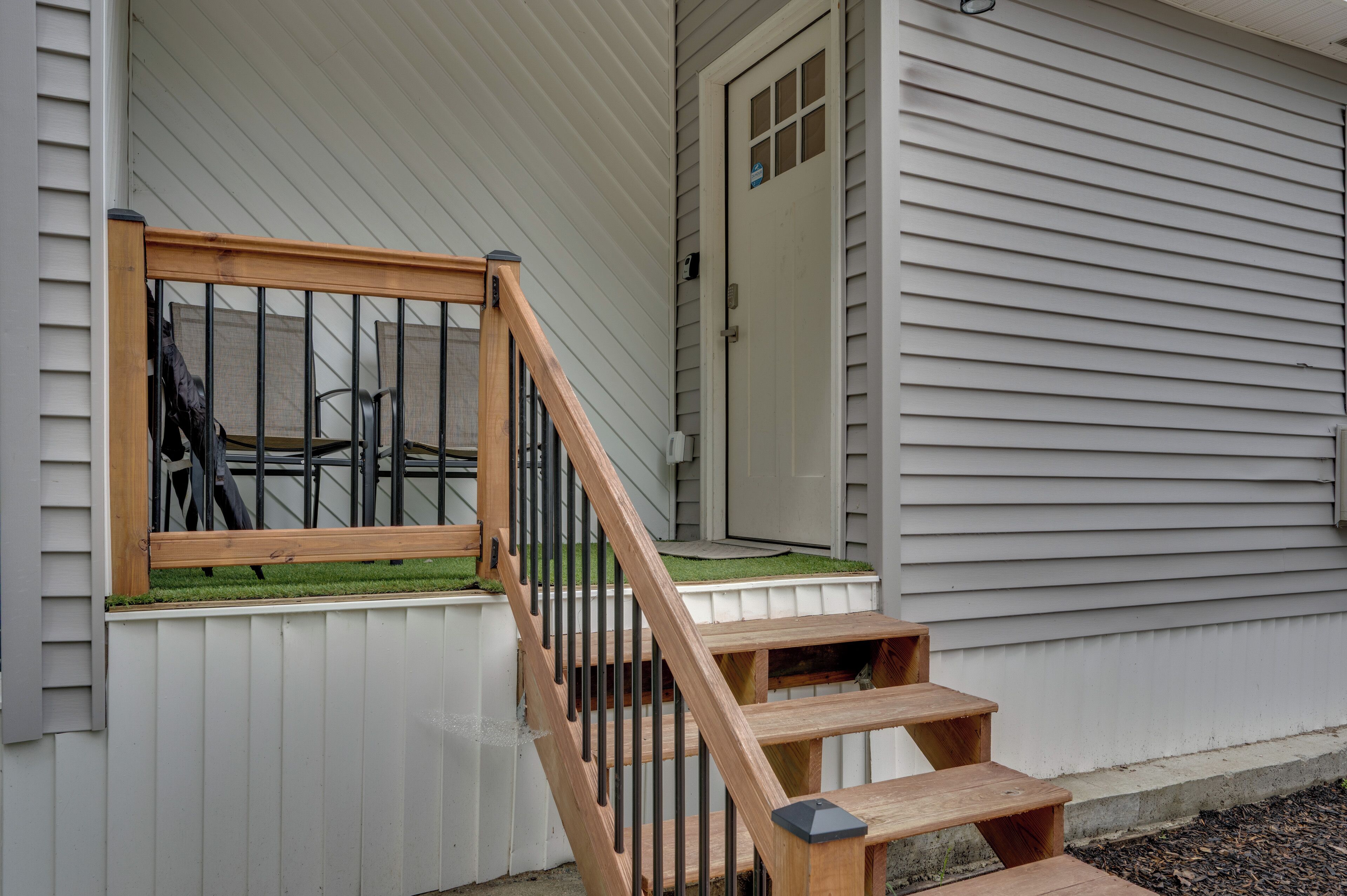 A wooden staircase leading to a porch with a window overlooking a grassy area.