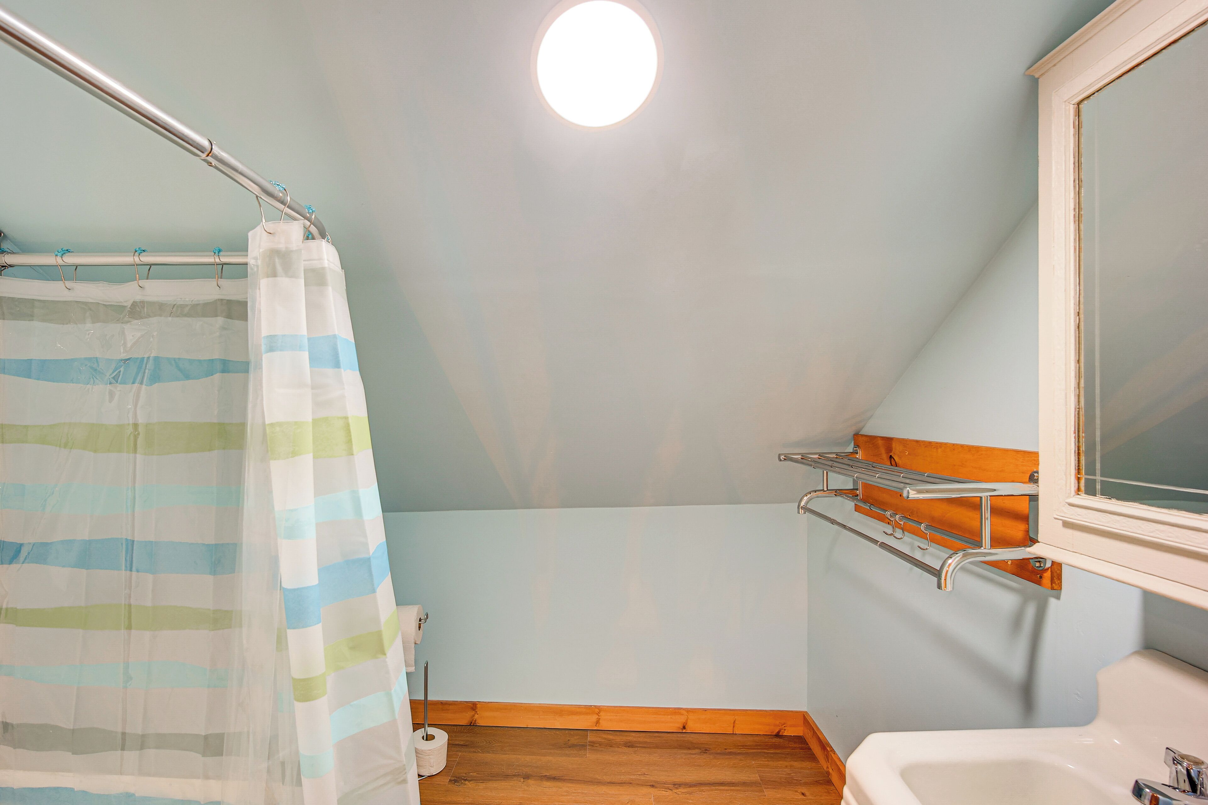 Een badkamer met douchegordijn, toiletrolhouder en wastafel.