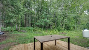 Eine Holzterrasse mit einem Tisch in bewaldeter Landschaft.