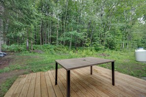 Une terrasse en bois avec une table, située dans une zone boisée.
