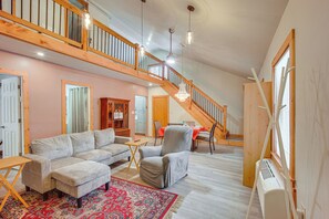 Ein geräumiges Wohnzimmer mit hoher Decke, einer Treppe und einem großen Fenster.