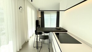 A modern kitchen with a dining area, featuring a black countertop, white walls, and a minimalist design. - Le Jolie 1 - Carraro Immobiliare Jesolo (Jesolo)