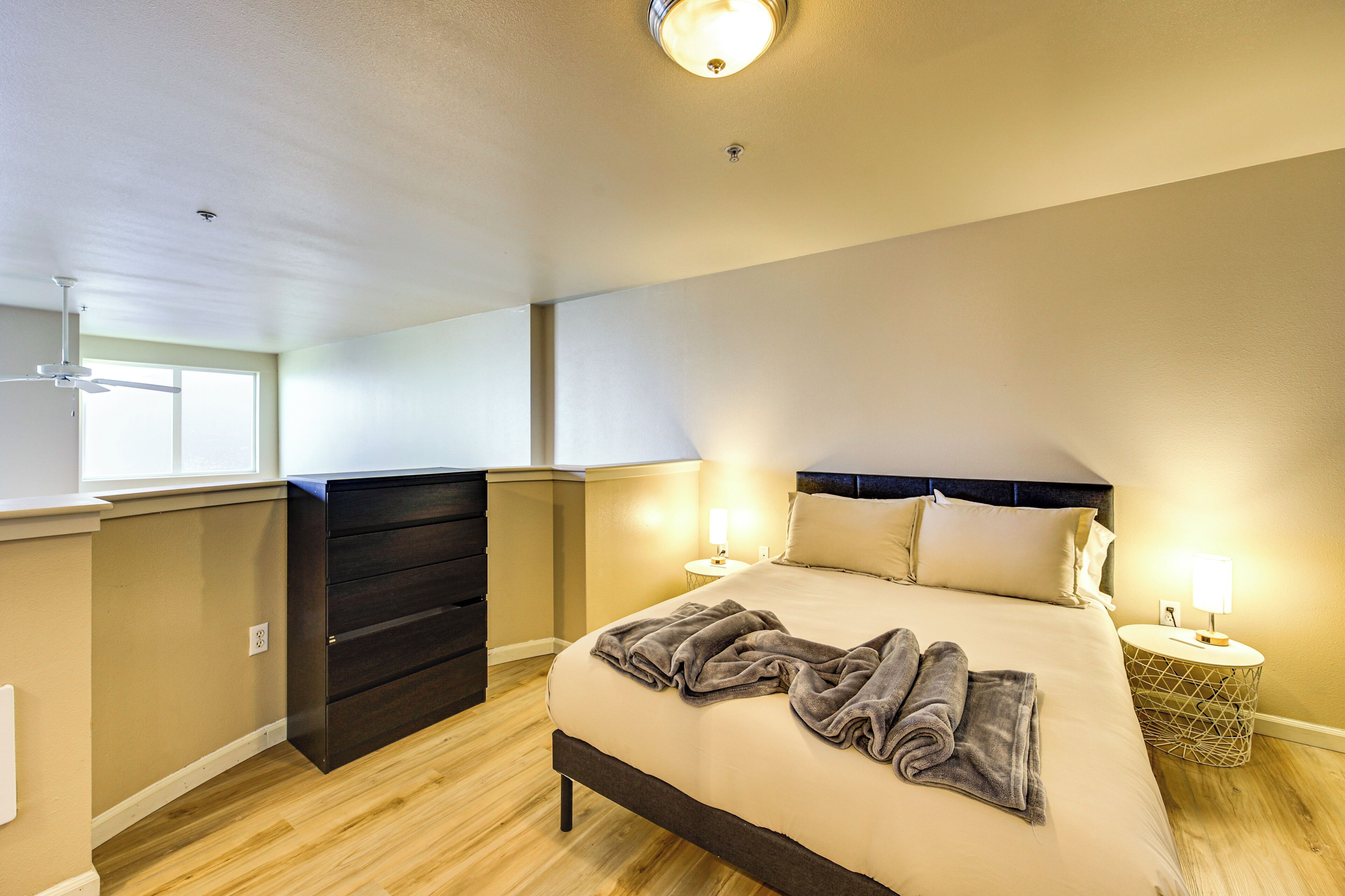 Ein Schlafzimmer mit einem großen Bett, Nachttischlampen, einem Schminktisch und einem Deckenventilator.