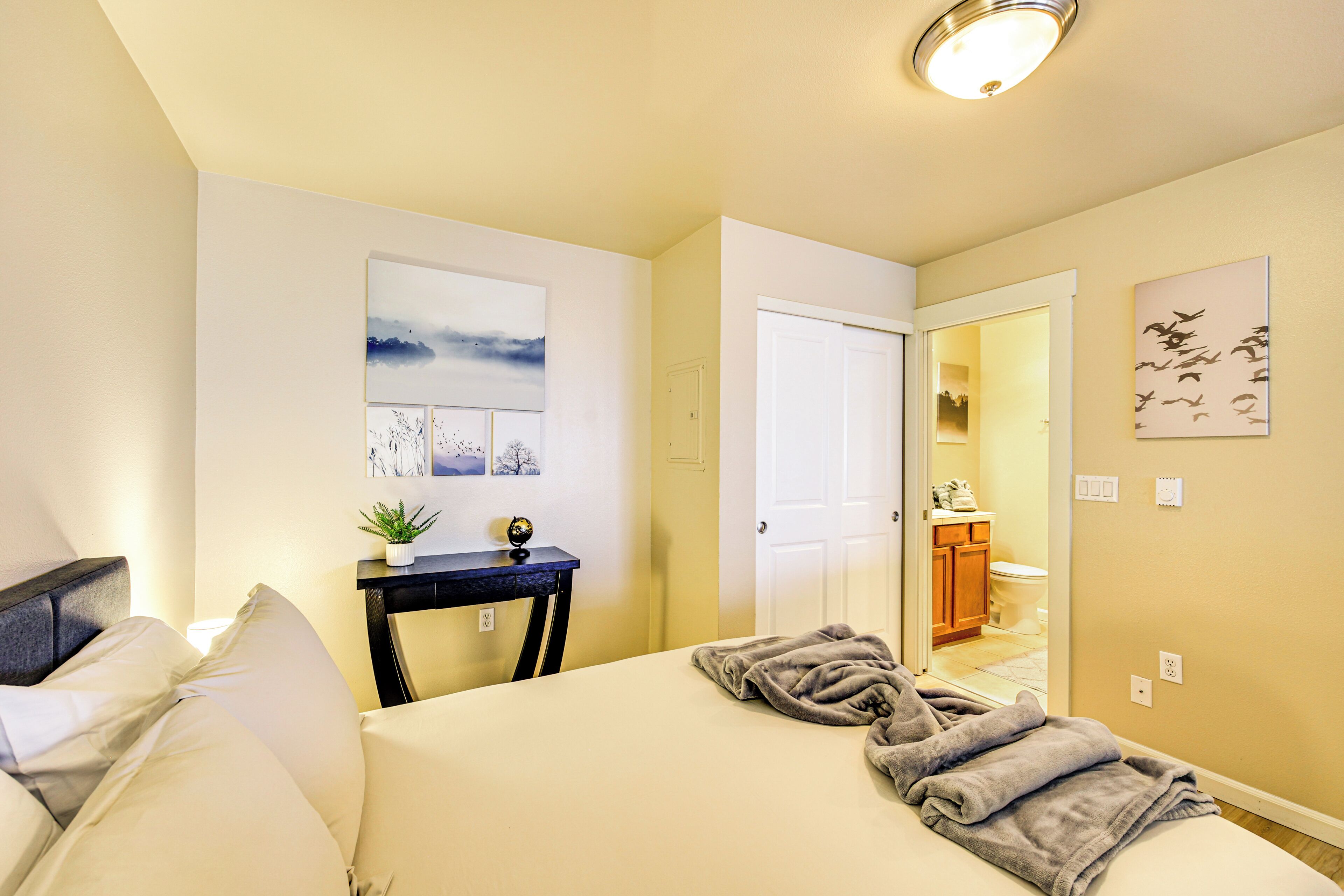 A hotel room with a bed, bedside table, and a view into the bathroom.