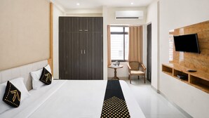 Ein Hotelzimmer mit Bett, Fernseher, Schreibtisch, Stuhl, Klimaanlage und Fenster.
