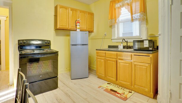 Cucina con pensili in legno, frigorifero in acciaio inossidabile, microonde e forno.