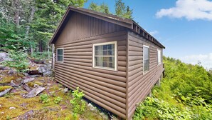 Eine Blockhütte mit Satteldach, zwei Fenstern und einer kleinen Veranda.