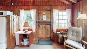 Ein Interieur einer Holzhütte mit einer Küchenzeile, einem Esstisch und einem Stuhl.