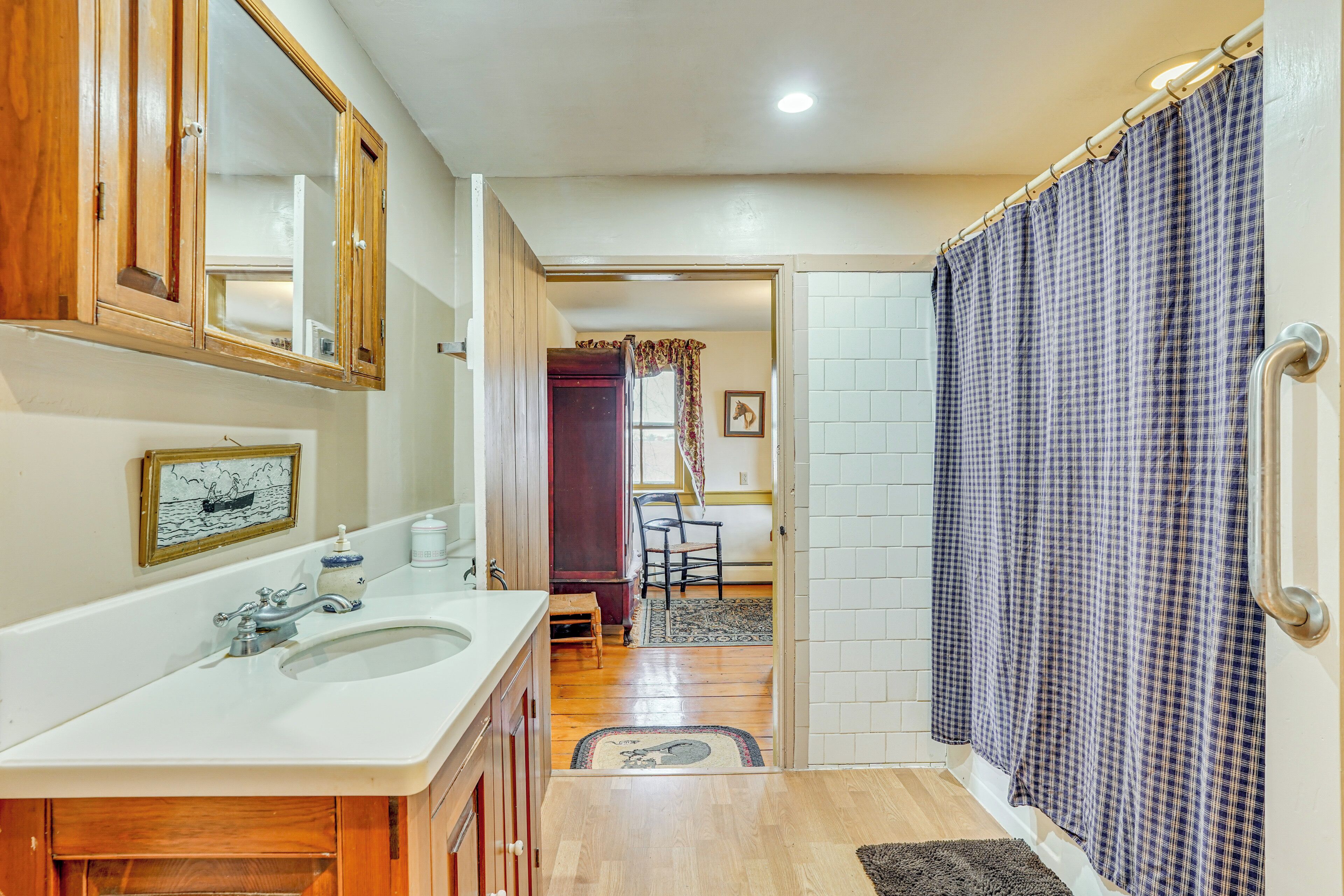A bathroom with a wooden vanity, a sink, and a shower curtain.
