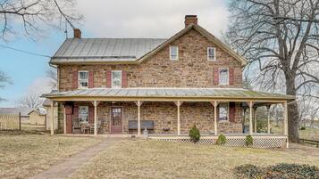 A stone house with a porch, a front door, and a small front yard.