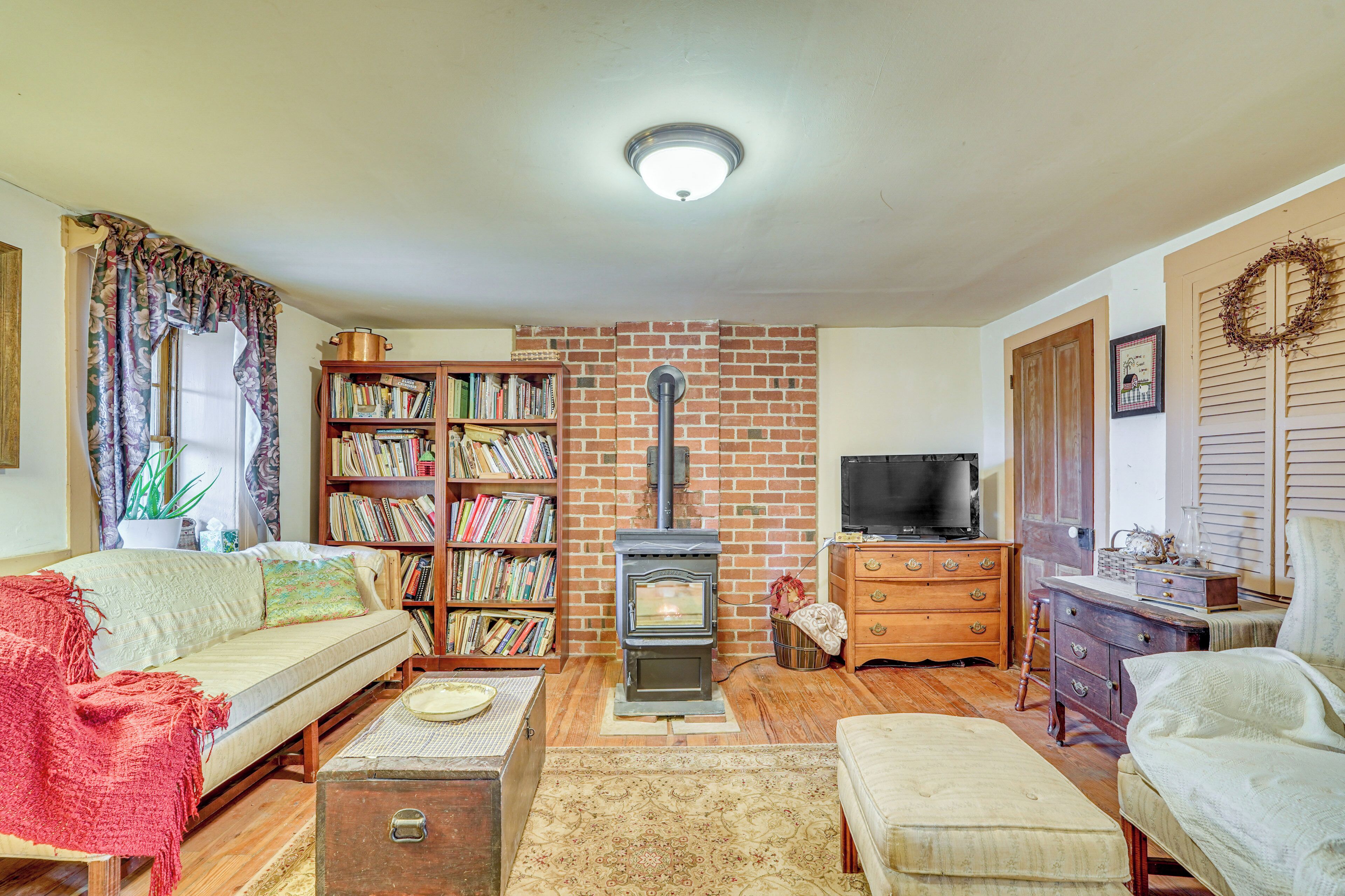 A cozy living room with a brick fireplace, a bookshelf, a sofa, and a television.