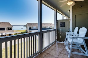 A balcony with a view of a lake, white Adirondack chairs, and a sign that says "Take Life." - Steps to Lake Conroe! Condo w/ Balcony & Views (Montgomery)