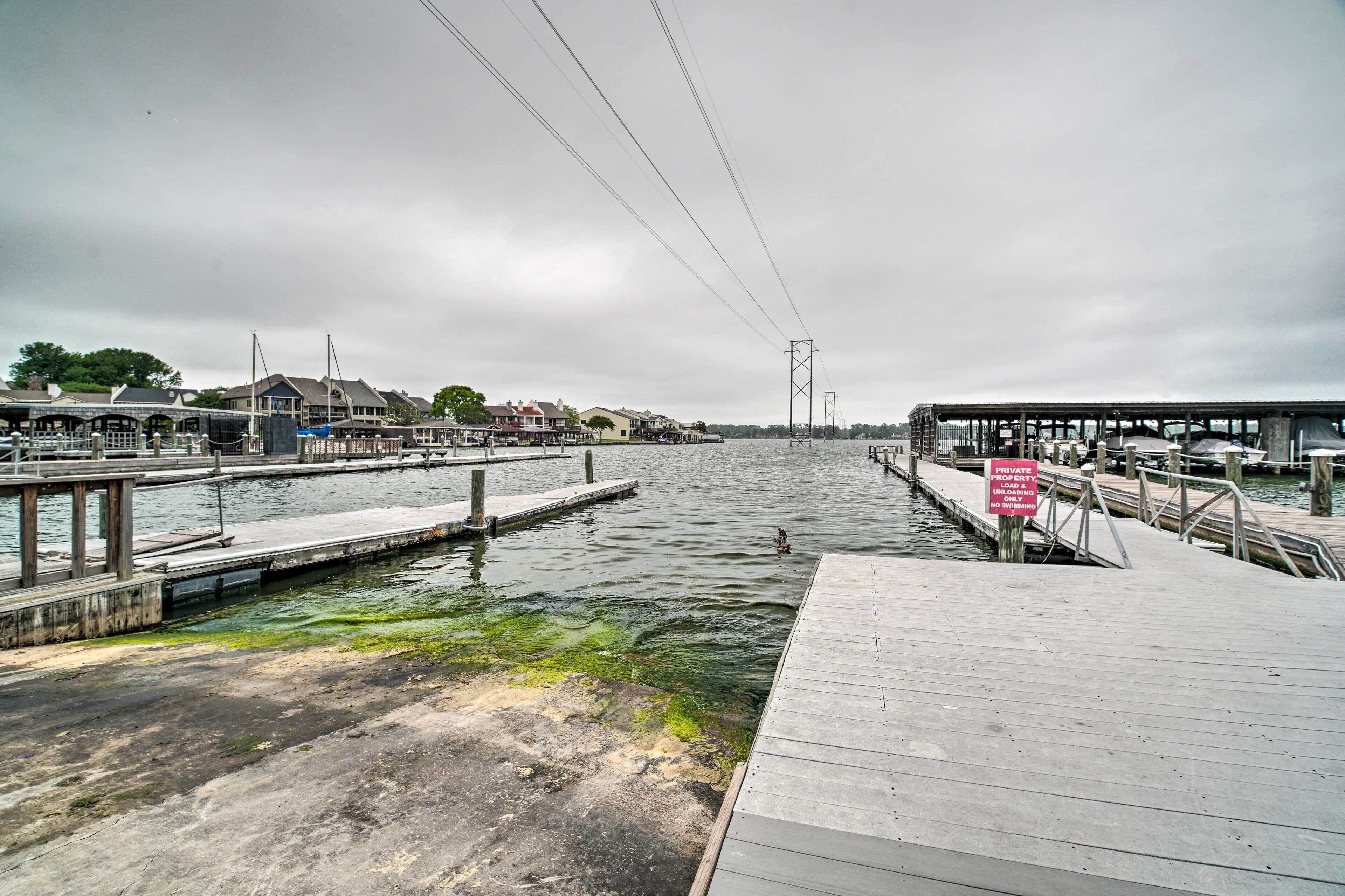 Een steiger aan het water met een bord ‘Privé aanmeren’, houten looppaden en een uitzicht op huizen aan de overkant.