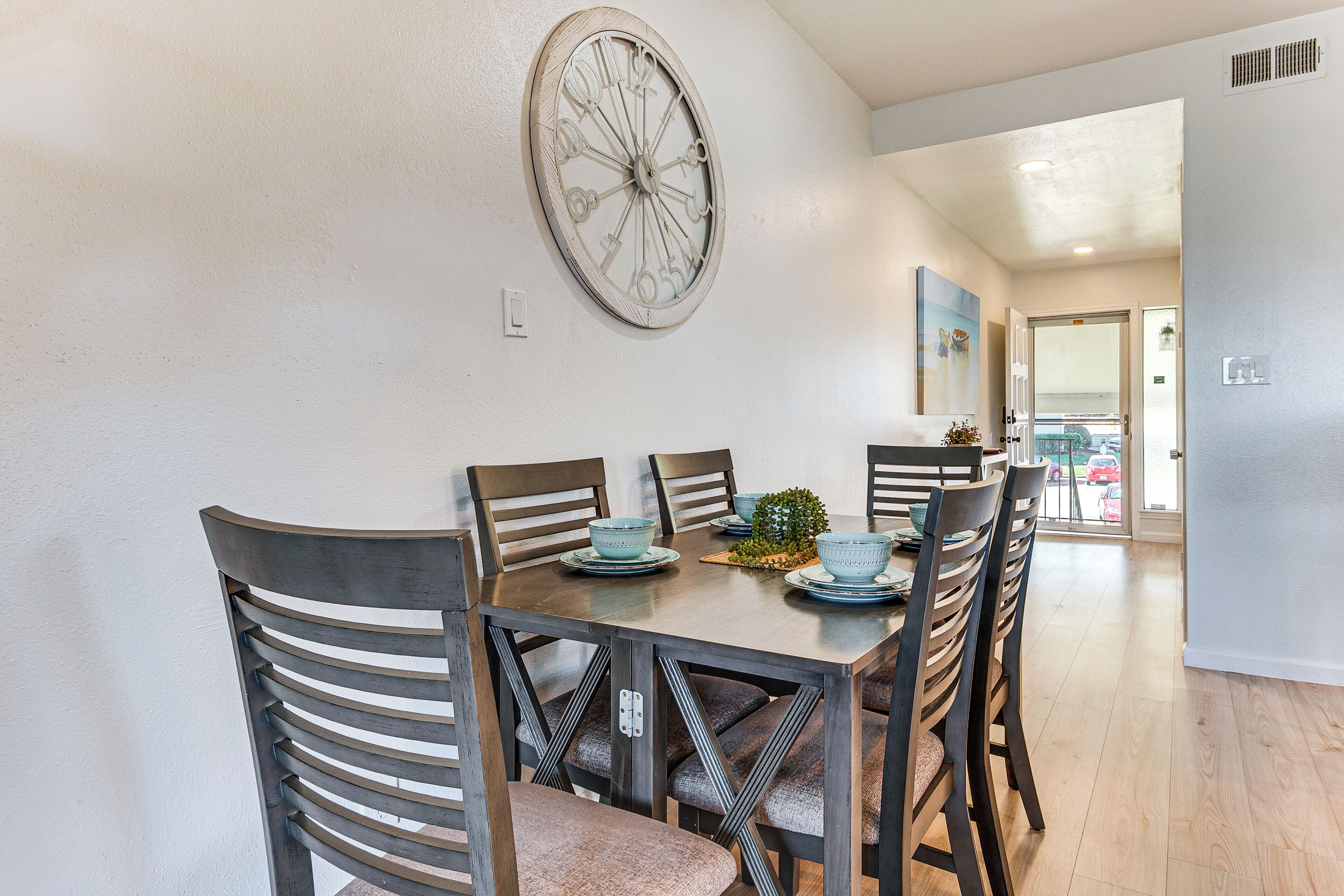 A dining area with a round table, six chairs, and decorative wall art.
