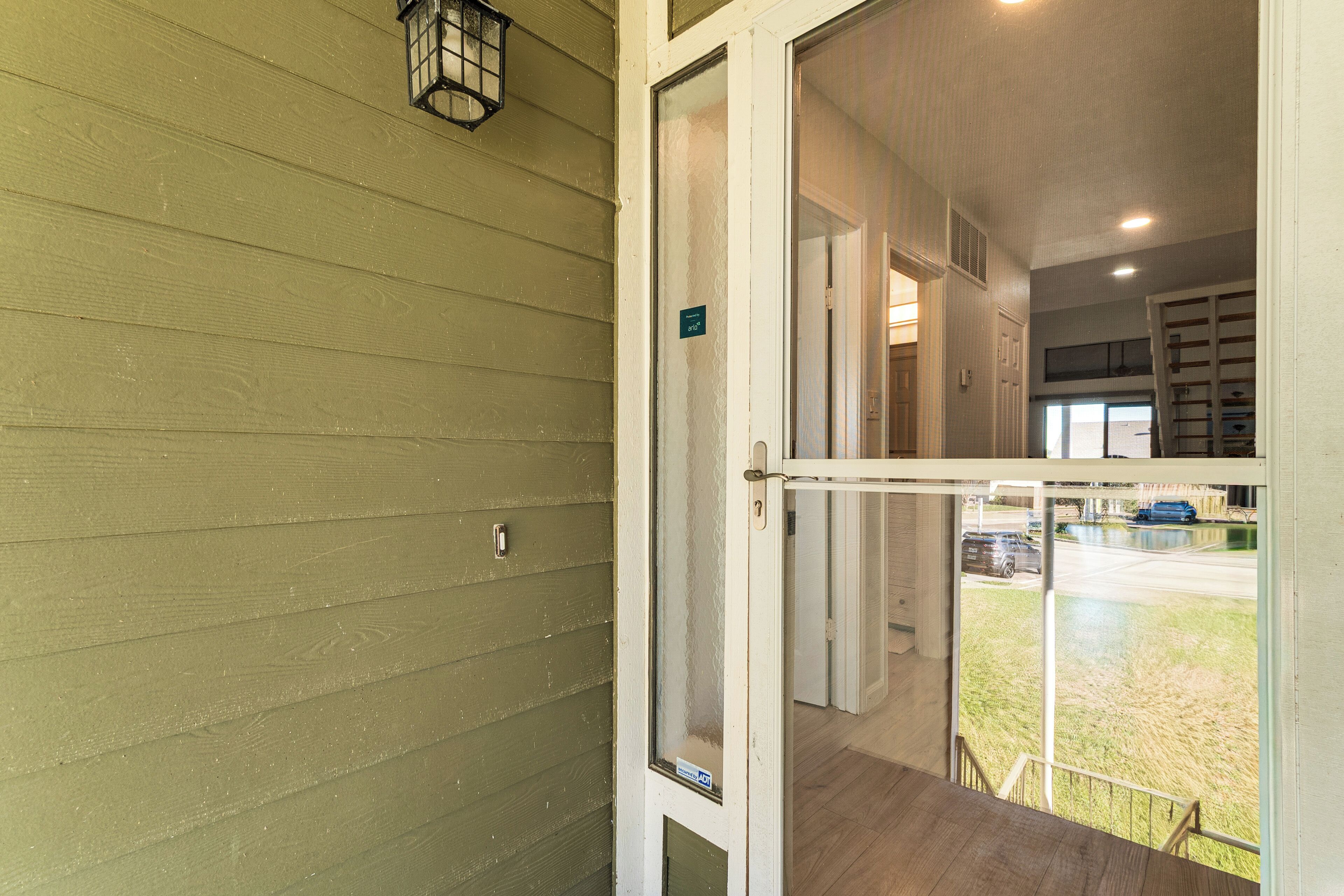 A hotel entrance with a green exterior wall, a glass door, and a view of the parking lot outside.