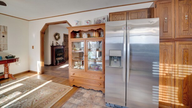 Una cucina con mobili in legno, un frigorifero in acciaio inossidabile e un pensile con stoviglie.