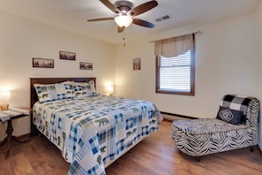 A bedroom with a bed, a chair, a ceiling fan, and wall art. - 5-acre Hocking Hills Hideaway! Pet-friendly Home (New Plymouth)