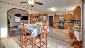 Un'ampia cucina con mobili in legno, un'area pranzo con tovaglia a quadri e una ventola a soffitto.