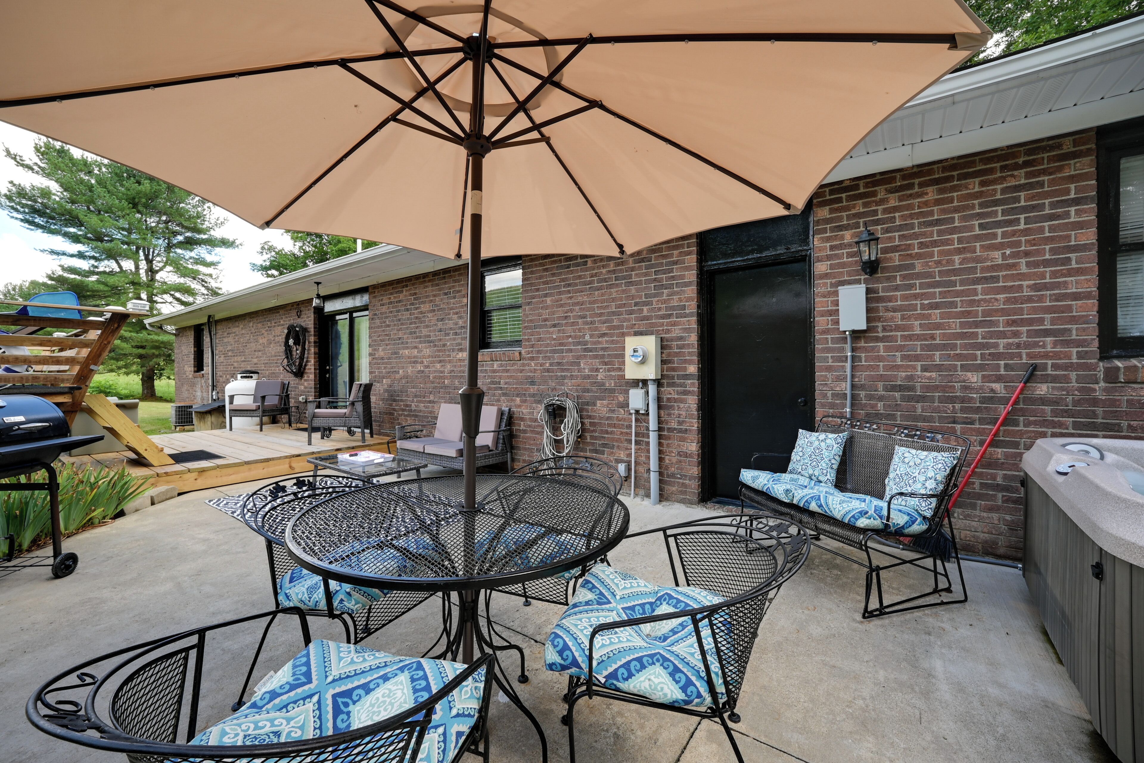 Un espace extérieur aménagé en terrasse, avec une table ronde en métal, des chaises rembourrées et un grand parasol.