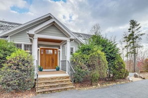 Une maison à deux étages avec un porche à l’avant, une porte en bois et un garage.