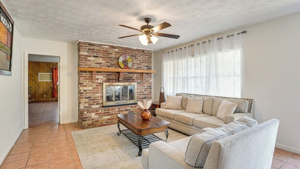 A living room with a brick fireplace, a ceiling fan, a sofa, and a coffee table. - Hike & Fish! Wooded Family Getaway in Interlachen (Interlachen)
