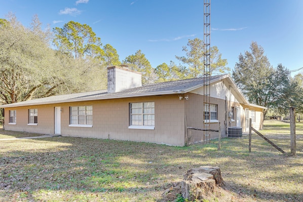 A single-story building with a brick exterior, a chimney, and a small front yard with a tree stump. - Hike & Fish! Wooded Family Getaway in Interlachen (Interlachen)
