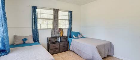 A bedroom with two beds, a dresser, and a ceiling fan.
