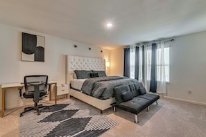 A bedroom with a bed, a desk, a chair, a rug, and a window with curtains. - Group Haven in Princeton! WFH Ready & Ample Space (Princeton)