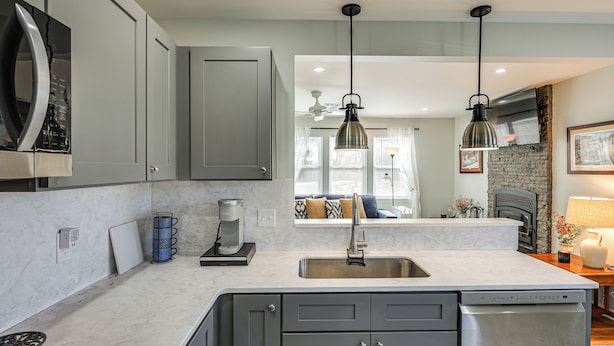 A modern kitchen with grey cabinets, a built-in dishwasher, a coffee maker, and a stone accent wall. - 3 Mi to Washington College! Updated Home w/ Patio (Chestertown)