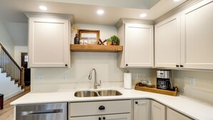 Una cocina moderna con armarios blancos, un lavamanos de acero inoxidable y una encimera de madera.