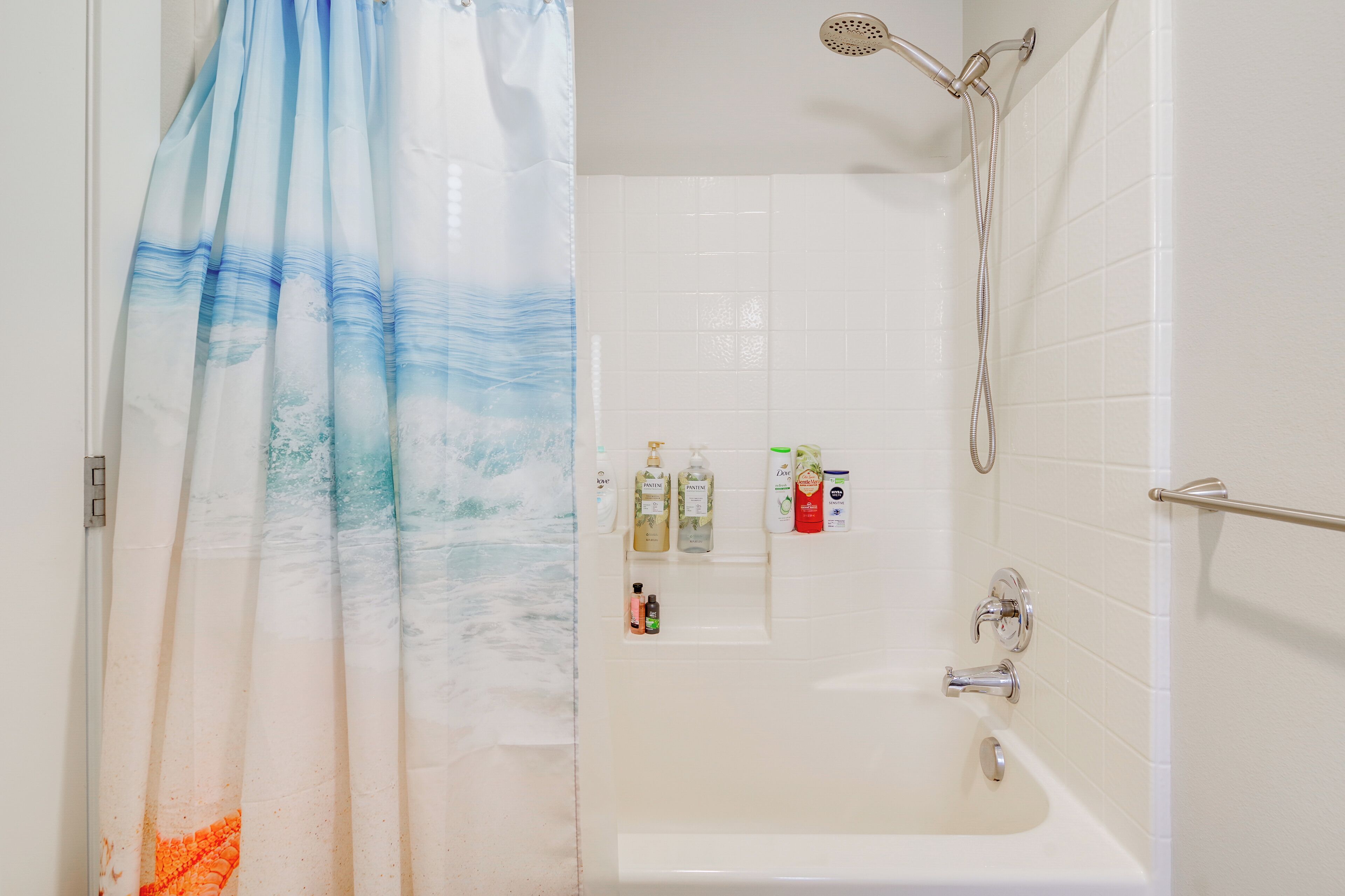 A bathroom with a shower, a bathtub, and toiletries on the wall.